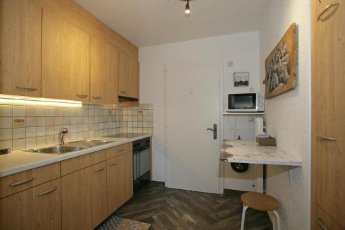 a kitchen with wooden cabinets and a sink and a chair at Apartments Haus Quelle in Leukerbad
