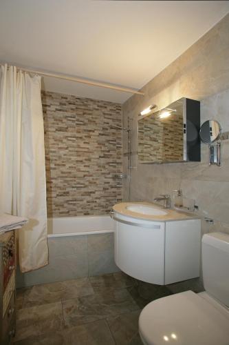a bathroom with a sink and a toilet and a tub at Apartments Haus Quelle in Leukerbad
