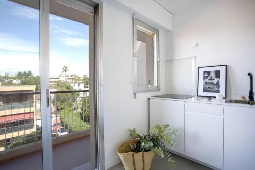 - une cuisine blanche avec une grande fenêtre et un évier dans l'établissement Juan les pins, près de la plage, à Antibes