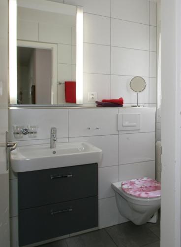a bathroom with a sink and a toilet and a mirror at Apartments Haus Quelle in Leukerbad