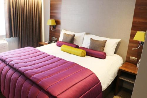 a hotel room with a large bed with colorful pillows at The Woodlands Event Centre in Wyboston