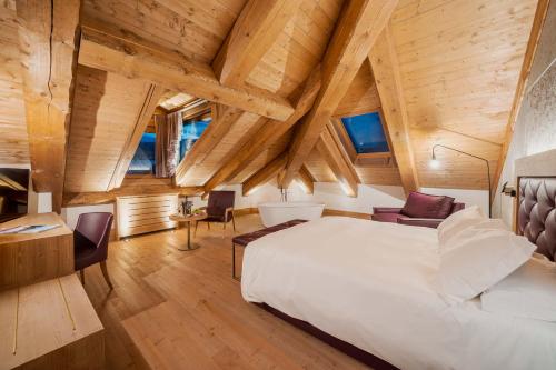 Schlafzimmer mit einem großen weißen Bett und Holzdecken in der Unterkunft Royal Hotel Cortina in Cortina d'Ampezzo