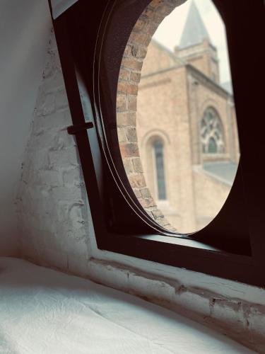 a round window with a church in the background at Lichtrijke loft bij restaurant Den Olifant in Ypres