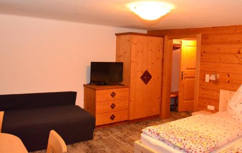 a bedroom with a couch and a tv on a dresser at Kleintödlinggut in Leogang