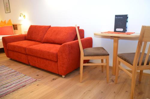 a living room with a red couch and a table with a laptop at Kleintödlinggut in Leogang