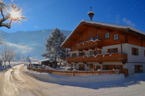 a large wooden house in the snow with a fence at Kleintödlinggut in Leogang