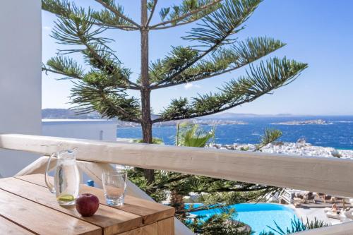 a wooden table with an apple and glasses on a balcony at Vencia Boutique Hotel in Mýkonos City