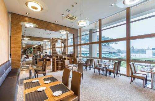 a restaurant with tables and chairs and large windows at ETO Park Hotel Business & Stadium in Győr