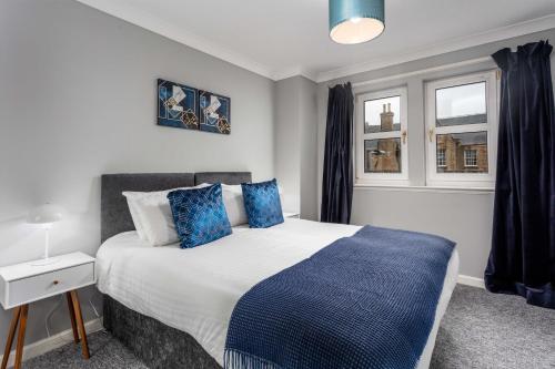 a bedroom with a large bed with blue pillows at Millbrae Residence - Donnini Apartments in Ayr