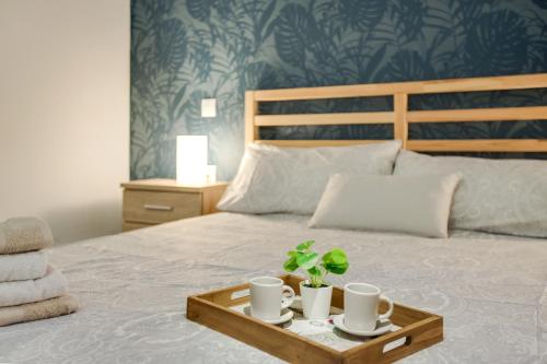 ein Bett mit einem Tablett mit Tassen und Pflanzen darauf in der Unterkunft 2b El Amore in Vecindario
