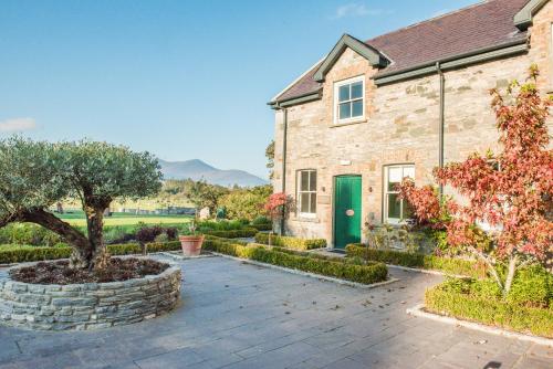 a stone house with a tree in a courtyard at Cahernane House Hotel in Killarney