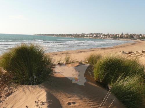 a view of a beach with grass and the ocean at La Perla di Sicilia in Marina di Modica