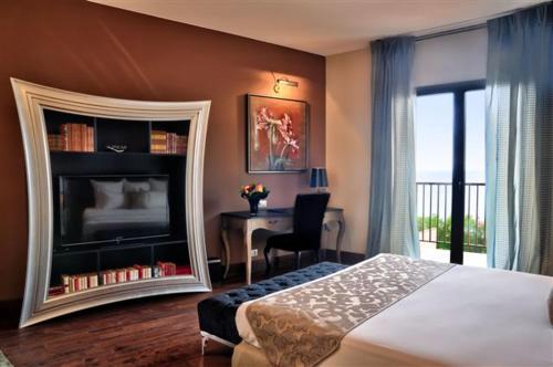 a bedroom with a bed and a desk with a fireplace at Hôtel Demeure Loredana in Saint-Florent