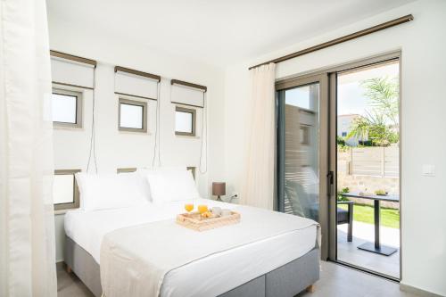 a white bedroom with a bed and a balcony at Lux Villa Nymphes Dioni, 30m from beach with Pool, BBQ and Play Area in Stavromenos