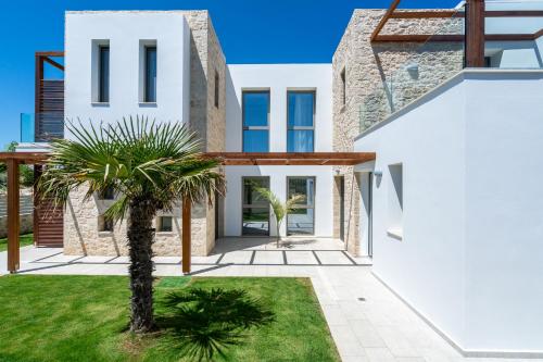 a white house with a palm tree in the yard at Lux Villa Nymphes Dioni, 30m from beach with Pool, BBQ and Play Area in Stavromenos