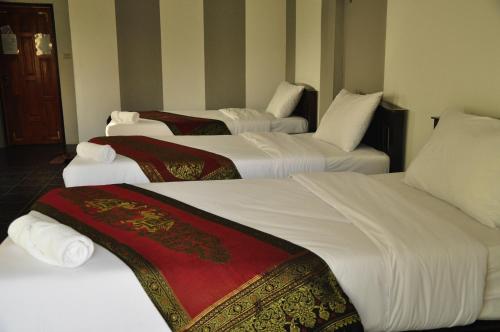 a group of four beds in a hotel room at Chiang Rai Khuakrae Resort in Chiang Rai