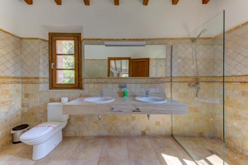 a bathroom with two sinks and a toilet and a mirror at Villa Vall Den March II in Pollença