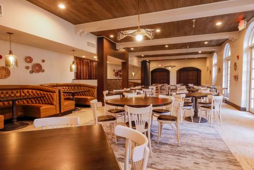 a restaurant with wooden tables and white chairs at Casa De Palmas, Trademark Collection by Wyndham in McAllen