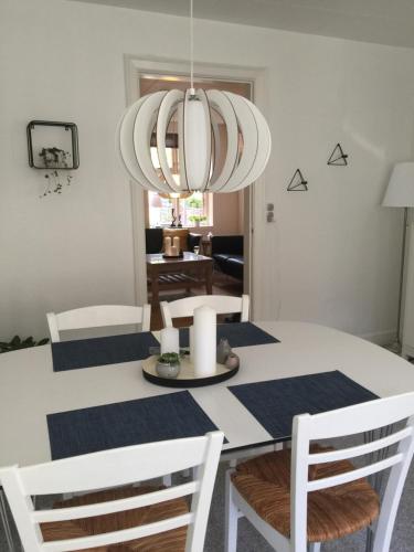 a dining room table with white chairs and a chandelier at Nakskov Overnatning in Nakskov