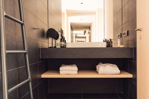 ein Badezimmer mit einem Waschbecken und einem Regal mit Handtüchern in der Unterkunft Hotel Milla Montis in Meransen