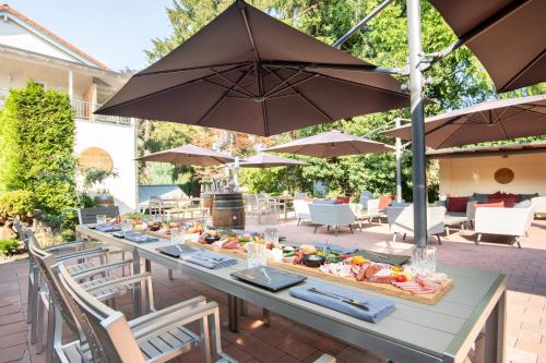 een lange tafel met eten op een patio met parasols bij Hotel Wegner - T h e culinary art hotel in Hannover