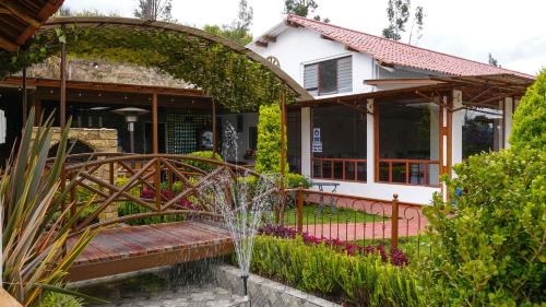 a garden with a fountain in front of a house at Hosteria Santa Ana in Azogues