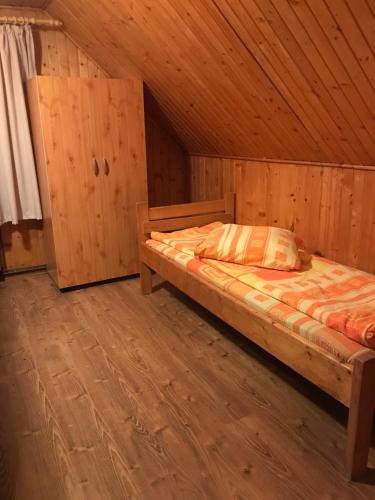 a bedroom with a bed in a wooden cabin at Hargitafürdői Vendégház in Harghita-Băi