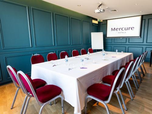 a conference room with a long table and red chairs at Hotel Mercure Roscoff Bord De Mer in Roscoff