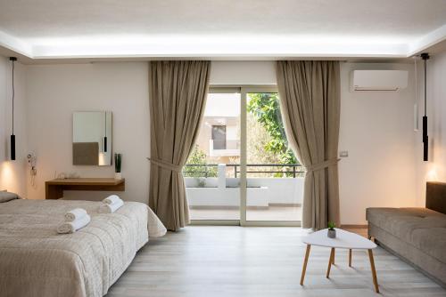 a bedroom with a bed and a couch and a window at Terinikos Hotel Junior Suites & Apartments in Ialyssos