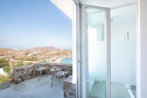 a room with a balcony with a view of the ocean at The Summit of Mykonos in Kalo Livadi