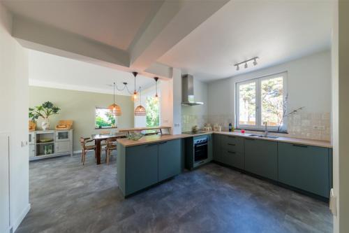 a large kitchen with blue cabinets and a dining room at Vakantiehuis Le Platane - in natuurgebied nabij Nijmegen in Beek