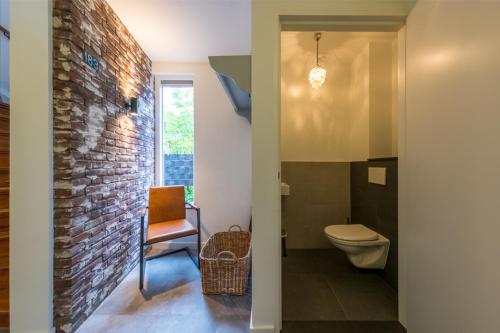 a bathroom with a toilet and a brick wall at Vakantiehuis Le Platane - in natuurgebied nabij Nijmegen in Beek