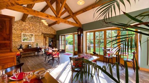 una sala da pranzo con tavoli, sedie e finestre di Les Granges Hautes Chambre d'hôtes de charme proche Sarlat a Saint-Crépin-et-Carlucet