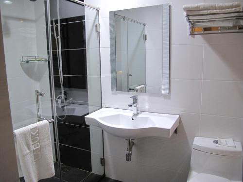 a bathroom with a sink and a shower and a toilet at Labuk Hotel in Sandakan