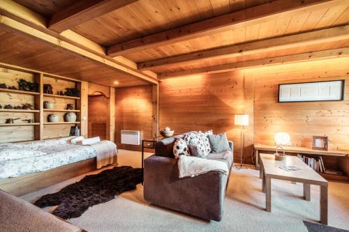 ムジェーヴにあるCosy and comfortable studio ski-in and walking distance from the slopesの木製の壁のベッドルーム1室、ベッド1台、ソファが備わります。