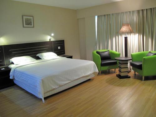 a hotel room with a bed and two green chairs at Labuk Hotel in Sandakan