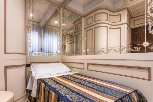 małą sypialnię z łóżkiem i lustrem w obiekcie Palazzina Veneziana w Wenecji