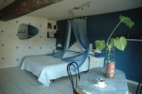 a bedroom with a bed and a table with a plant at Chambre d'Hôte La Boulière in Martigné-Ferchaud