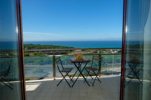 a balcony with a table and chairs and the ocean at Summer in Paradise - Sea View and Pool in Ericeira in Ericeira