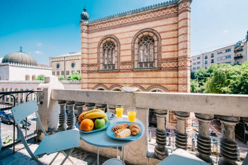 ブダペストにあるJACUZZI SINAGOGA viewのバルコニーのテーブルにフルーツとジュースの盛り合わせ