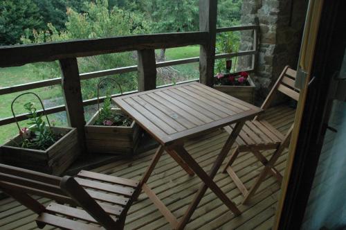 a wooden table and two chairs on a deck at Chambre d'Hôte La Boulière in Martigné-Ferchaud