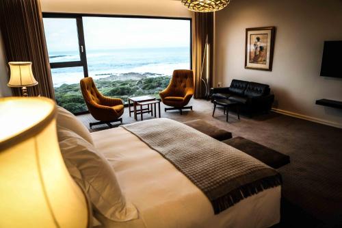 a hotel room with a bed and a large window at Schulphoek Seafront House in Hermanus