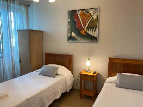 a bedroom with two beds and a picture on the wall at Hospedaria Isaias in Angra do Heroísmo