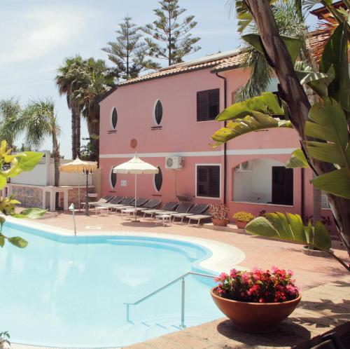 einen Pool vor einem rosa Haus in der Unterkunft Costa degli Dei Resort in Capo Vaticano