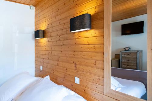 a bedroom with a wooden wall with two beds at Hôtel Les Côtes, Résidence Loisirs et Chalets in Morzine