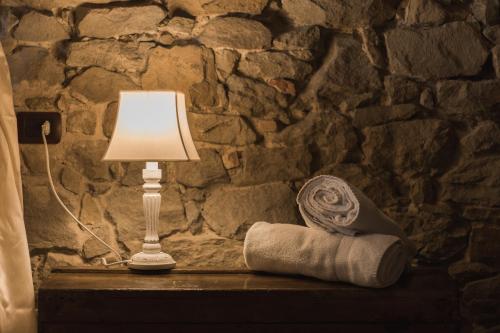 a lamp sitting on a table next to a stone wall at EcoResort Il Cantico della Natura in Magione