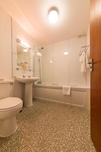 a bathroom with a toilet and a sink and a tub at Castletown Hotel in Castletown