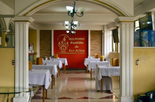 un comedor con mesas blancas y una pared roja en Hotel y Restaurante Castillo de los Altos, en Quetzaltenango