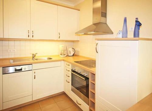 una cucina con armadi bianchi e lavandino di Residenz-Ostseestrand-Wohnung-4-9624 a Kühlungsborn