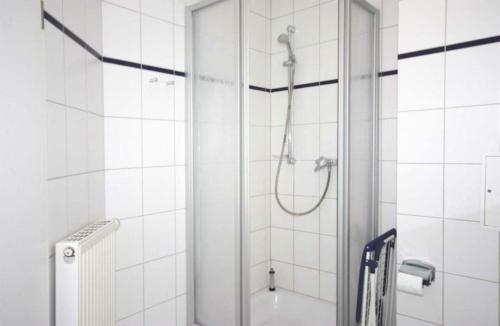 een douche in een wit betegelde badkamer bij Strandschloesschen-Haus-II-WE-11-9644 in Kühlungsborn